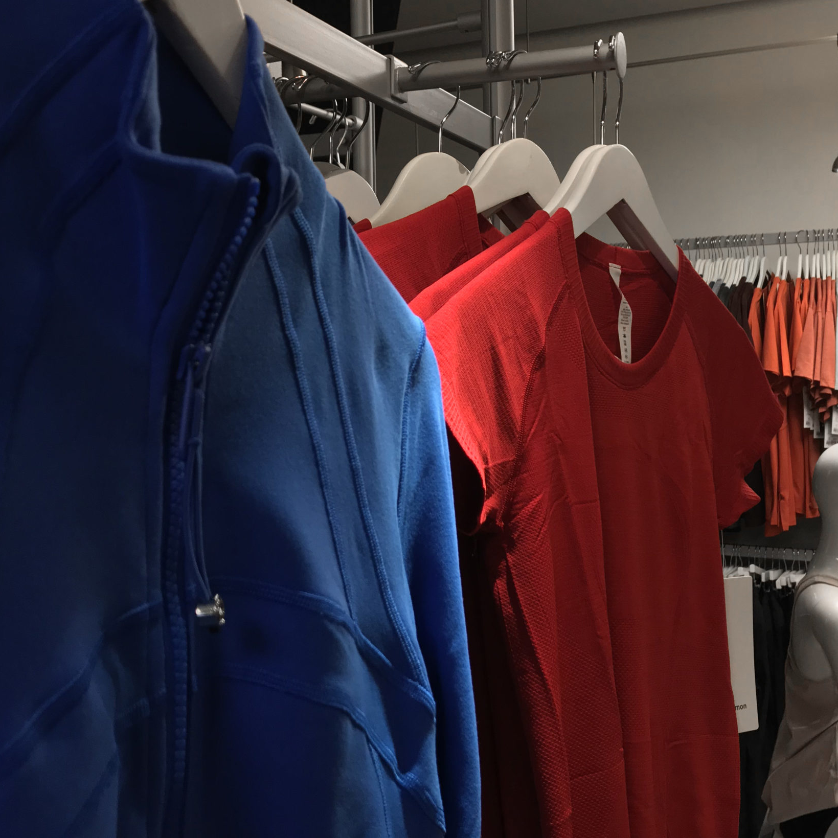 Light jackets and workout shirts on hangers, displayed at the Zenergy boutique.
