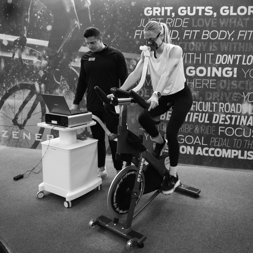Woman on exercise bike with trainer inside the Zenergy ZENLAB.
